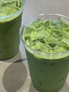 two plastic cups filled with green smoothies