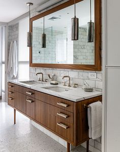 a bathroom with two sinks and a large mirror on the wall above it is white tile flooring