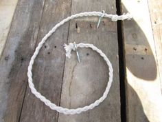 a white rope with two screws on it sitting on top of a wooden floor