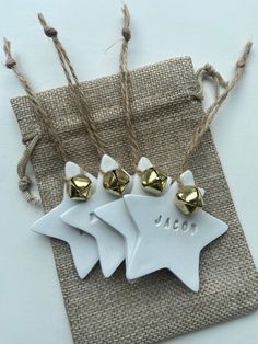 three white ceramic star ornaments with gold bells on twine string and burlap