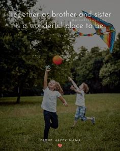 two young children playing with a kite in the grass, one has his arms up