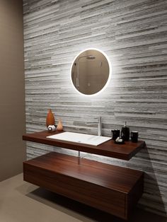 a bathroom with a sink, mirror and lights on the wall above it's counter