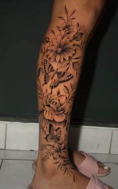 a woman's foot with flowers and butterflies on the top of her leg, in black