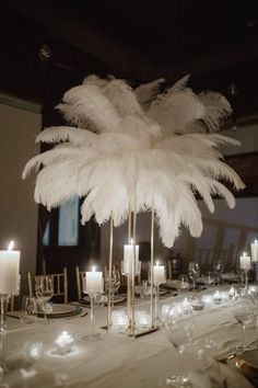 a table with candles and white feathers on it