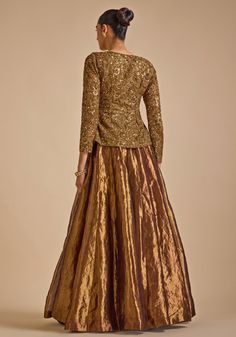 Step into elegance with Gold Embroidered Jacket Set. Crafted from luxurious blended silk, this stunning jacket features intricate zardozi and sequin embroidery detailing that exudes sophistication. The jacket's opulent design is perfectly complemented by a flared skirt, creating a harmonious blend of tradition and contemporary style. A perfect indo western outfit a bride or bride to be for Cocktail parties or Reception Night. Composition : Jacket - Blended Silk, Skirt - Tissue Care: Dry Clean On Gold Gown With Intricate Embroidery And Long Sleeves, Gold Long Sleeve Gown For Reception, Gold Long Sleeve Gown With Zari Work, Gold Zari Work Long Sleeve Gown, Party Wear Embellished Long Sleeve Sharara, Party Wear Long Sleeve Embellished Sharara, Embellished Long Sleeve Sharara For Party Wear, Long Sleeve Embellished Sharara For Party Wear, Formal Tissue Silk Lehenga For Eid