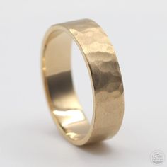 a gold wedding ring with a textured finish on the outside, and a plain surface