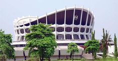 a large building sitting on top of a lush green field next to trees and bushes