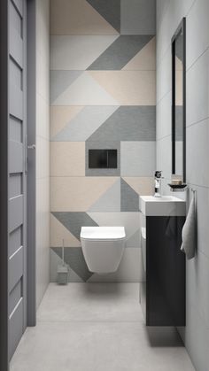 a bathroom with grey and white tiles on the wall, toilet, sink and mirror