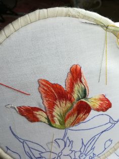 a close up of a embroidery on a piece of cloth with flowers in the center