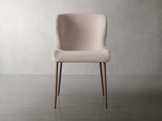 a pink chair sitting on top of a floor next to a white wall and wooden legs