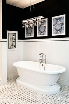 a white bath tub sitting next to two pictures hanging on the wall in a bathroom