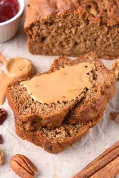 two slices of banana bread with peanut butter and pecans around them on wax paper