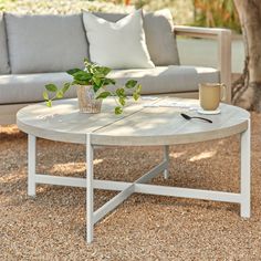 a white coffee table sitting on top of a gravel covered ground next to a couch