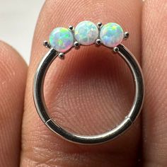 three opal stone ring sitting on top of someone's finger