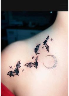 a woman's back shoulder with bats flying around the moon and stars on it