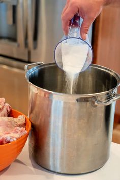 a person pouring milk into a pot with meat in it