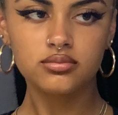 a close up of a person with large hoop earrings on her head and nose piercings