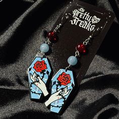 Gothic Witchy Rose Coffin Dangle earrings (Fishhook closure) with blue and red coordinating glass beads Charms are acrylic, beads are glass, Fishhooks, hoops & Components - Stainless Steel, hypoallergenic, lead and nickel free. All jewelry sold by LD Nails // The Pretty Freaks is designed and handmade in house. Charms/Pendants are purchased from jewelry supply shops, I cut and bend my own wires, chains and components. Since I am not a machine there may be very slight variances in lengths listed. Due to the personal nature of earrings and in the interest of hygiene, all sales are final! Silly Earrings, Spooky Outfits, Coffin Earrings, Country Nails, W Shoes, Weird Jewelry, Cute And Spooky, Gothic Rose, Love Earrings