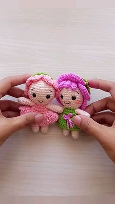 two small knitted dolls being held in their hands