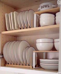 dishes and bowls are stacked on wooden shelves