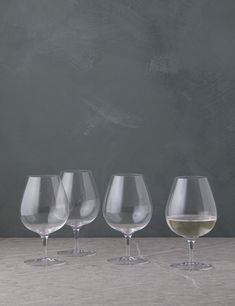 three wine glasses sitting next to each other on a table