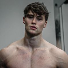 a shirtless young man is taking a selfie in the mirror