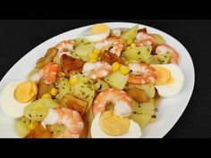 a white plate topped with shrimp, potatoes and hard boiled egg shells covered in seasoning