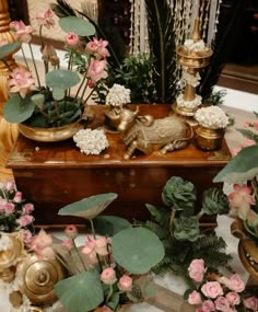 there are many flowers and plants in the vases on this table, along with other decorative items