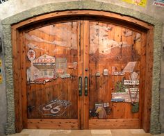 two wooden doors with stickers on them in front of a stone and wood building