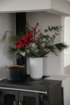 a black stove top oven sitting next to a white vase filled with flowers and greenery