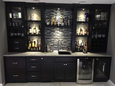 a very nice looking kitchen with some bottles on the wall and cabinets in it,