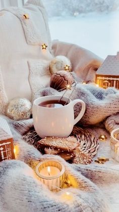 a cup of coffee sitting on top of a blanket next to christmas decorations and candles