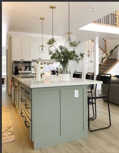 a kitchen with an island in the middle and stairs leading up to the second floor