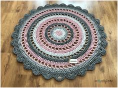 a circular crocheted rug is shown on the floor in pink, gray and white