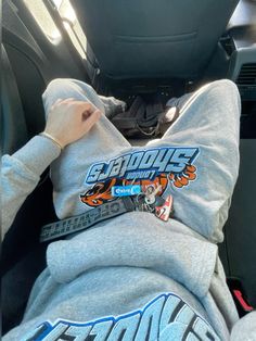 a person is sitting in the back seat of a car wearing a hoodie with an orange tiger on it