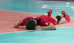 a volleyball player laying on the court with his hand up