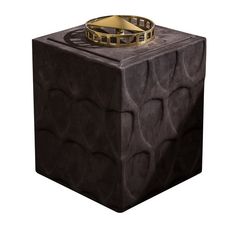 a ring is sitting on top of a black cube with gold rings around it's edges