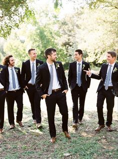 a group of men standing next to each other wearing suits and ties with trees in the background