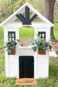 a white dog house with potted plants in it