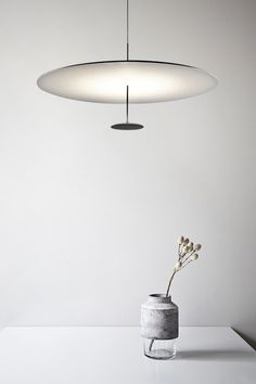 a vase with flowers in it sitting on a table next to a hanging light fixture