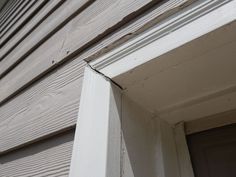 an open window on the side of a building with white paint and wood trims