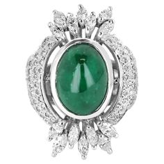 As regal as can be, this estate emerald and diamond cocktail ring is inspired by the Victorian period. It is quite a luxurious work of art and a true showstopper. A natural Colombian emerald cabochon is the center of attention and displays beautiful shine and brilliance. The focal emerald weighs a large 5.10cts and has incredible medium-dark color and very good clarity. Enhancing the center gem are one hundred-fifteen, round diamonds that follow the shape of the ring. The diamonds face up comple Emerald Cabochon, Diamond Face, Diamond Cocktail Ring, Victorian Period, Gold Cocktail Ring, Colombian Emeralds, Diamond Cocktail Rings, Marquise Diamond, Dark Color