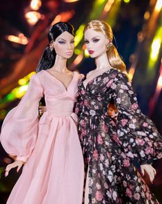 two barbie dolls standing next to each other