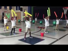 young children are playing with glow sticks in an indoor gym