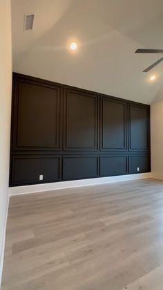 an empty room with wood paneling and ceiling fan