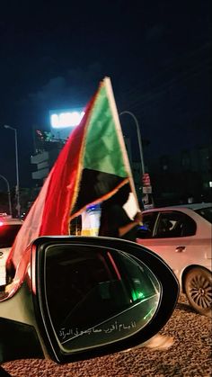 a car with a flag on it's side mirror in the middle of a street