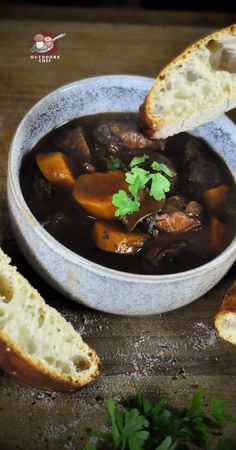 a bowl of stew with bread and parsley on the side, ready to be eaten