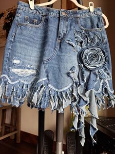 an old pair of jean shorts with flowers on them hanging from a clothes hanger