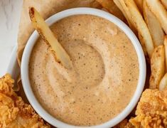 a white bowl filled with dipping sauce next to french fries