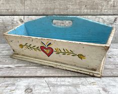 an old wooden box with painted designs on the sides and bottom, sitting on a wood surface